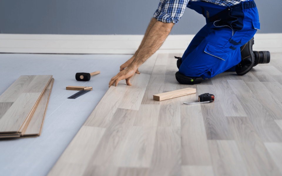 Profesional instalando pisos de madera, utilizando herramientas especializadas para asegurar una colocación precisa y un acabado perfecto.