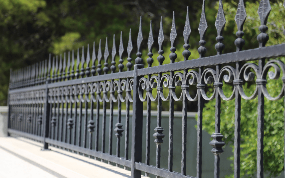 Portón de hierro forjado con detalles decorativos, instalado en un entorno exterior, resaltando la calidad y la seguridad de los trabajos de herrería profesional.