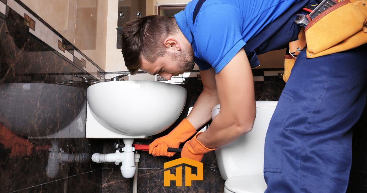 Plomero profesional reparando una fuga debajo del fregadero con herramientas especializadas. Soluciones rápidas y eficientes para problemas de plomería