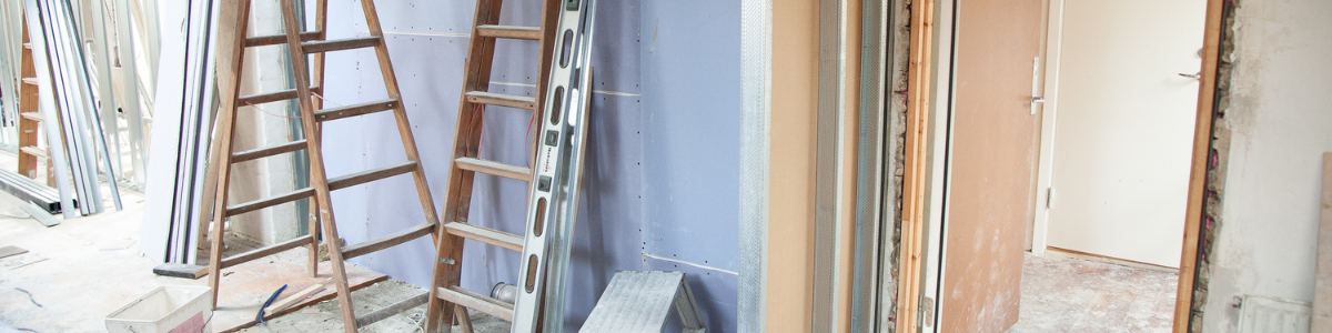 Persona pintando el interior de su casa con una brocha, aplicando pintura en la pared con cuidado.